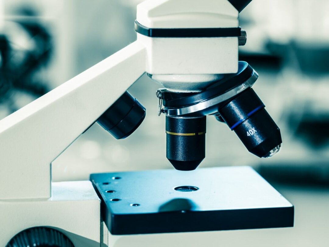 Close-up of microscope objective lenses in a teal-toned laboratory